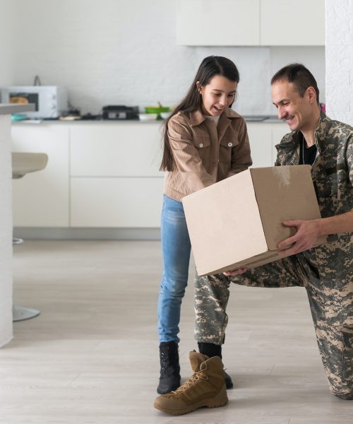 Military parents with daughter hugging, near cardboard boxes